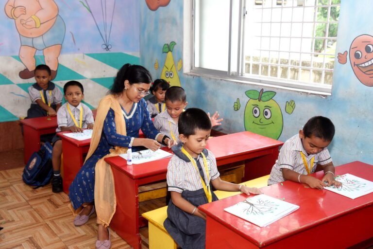 Teacher helping kindergarten children with a paper craft activity at St. Xavier's Public School, Haldia