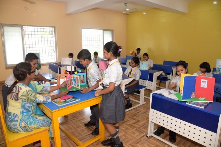 Teacher reviewing pupils' handmade project models in class