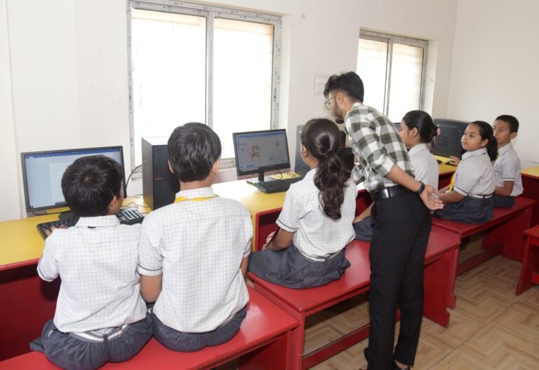 Teacher helping pupils at the computers in the school computer lab