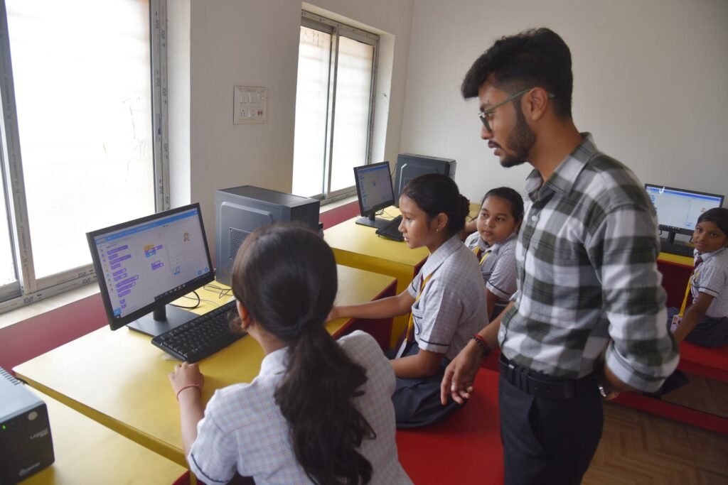 Teacher guiding pupils at a computer in the school computer lab