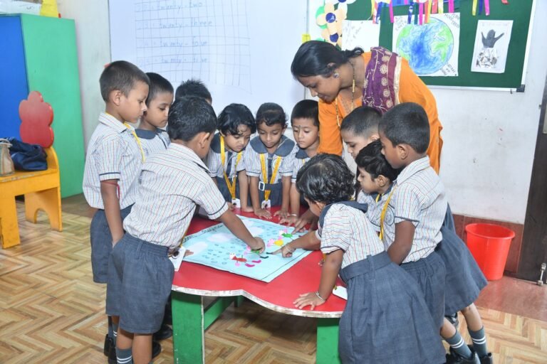 Teacher and kindergarten children around a table with a collage